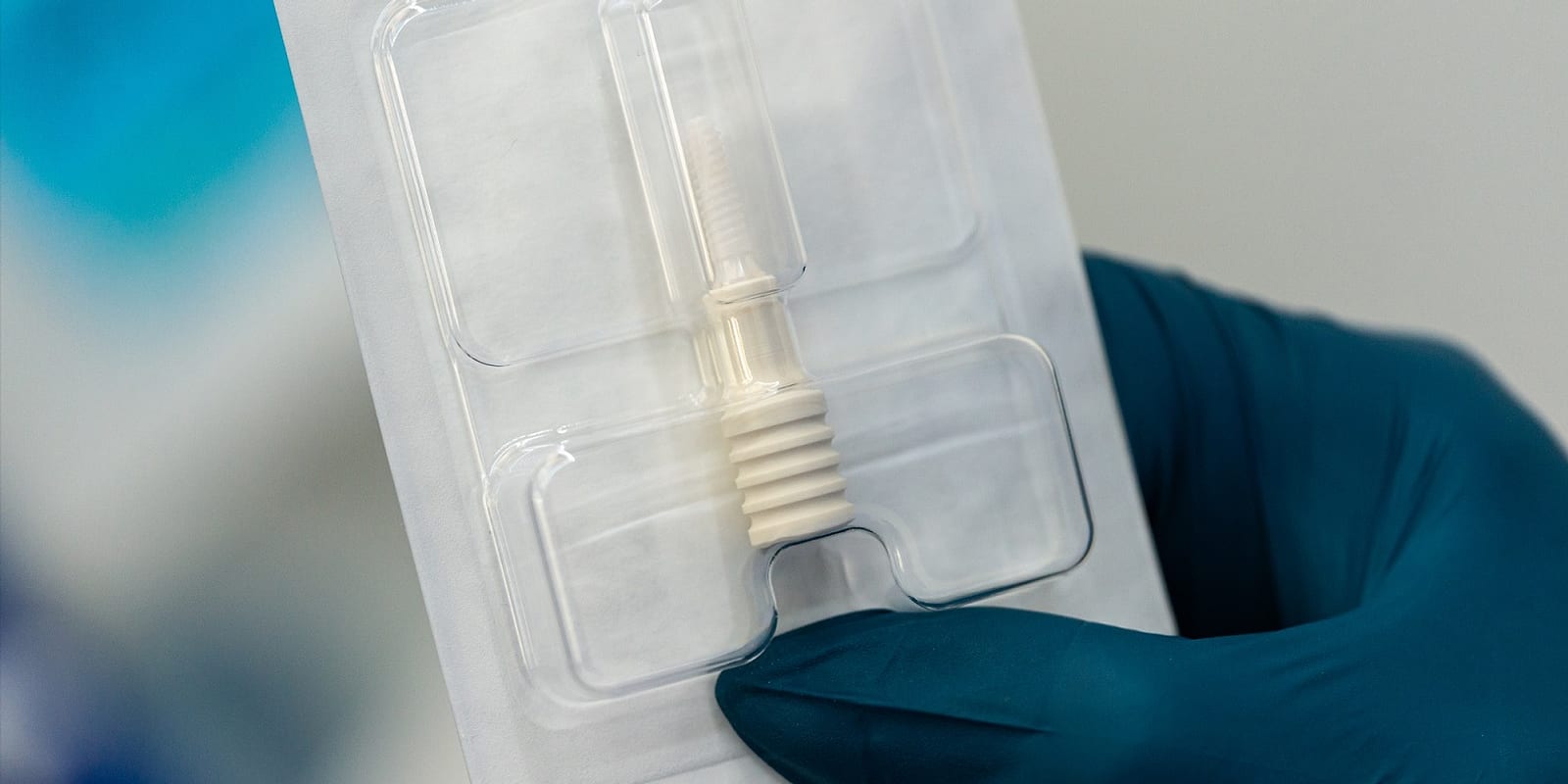 Implant dentar ceramic din zirconiu în ambalajul steril, ținut de medic înainte de inserare